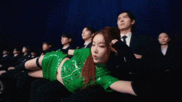 a group of women in green skirts are dancing on a stage in front of a blue curtain