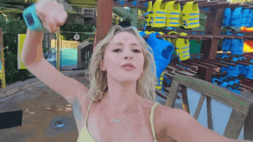 a woman in a yellow bikini is standing in front of a shelf of life vests