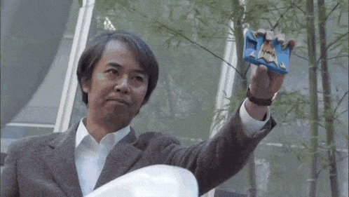 a man in a suit is holding a blue object in his hand with the letter j on it