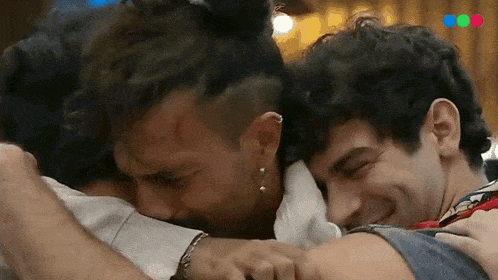a group of three men hugging each other with the letters mc on the bottom left