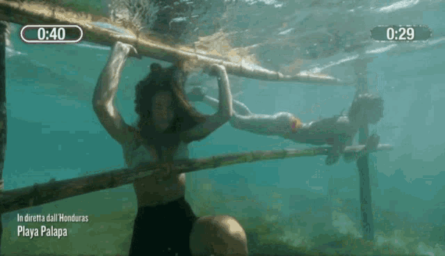 a woman is hanging from a wooden bar in the water with a time of 1:40