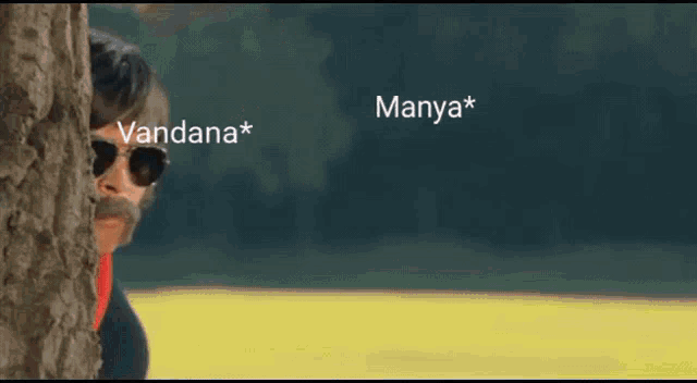 a man with sunglasses and a mustache peeking out from behind a tree with manya * written on the bottom