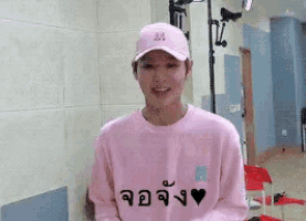 a young man wearing a pink hat and a pink sweater is smiling .