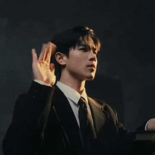 a man in a suit and tie is making a gesture with his fingers