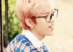 a young man wearing glasses and a striped sweater is smiling .