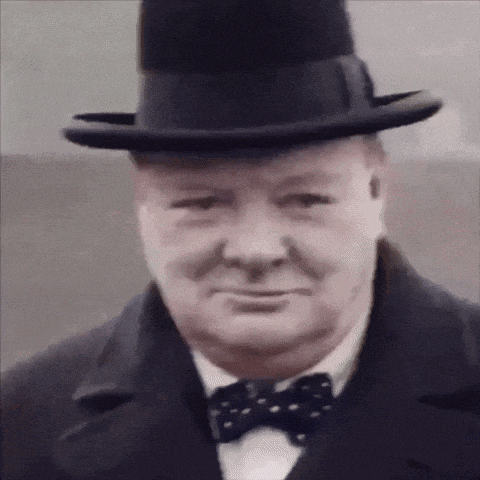 a man wearing a hat and a bow tie is looking at the camera .