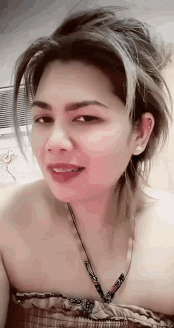 a close up of a woman wearing a necklace and a strapless top .