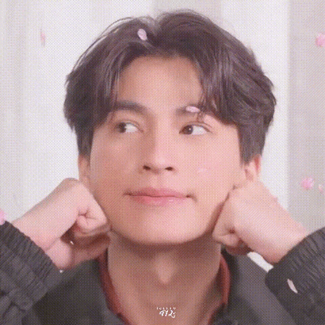 a young man is making a funny face with his hands on his face .