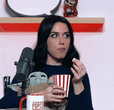 a woman is eating popcorn in front of a microphone