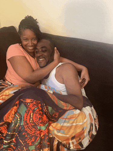 a man and a woman are laying on a couch under a colorful blanket