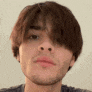 a close up of a young man 's face with a beard and long hair .