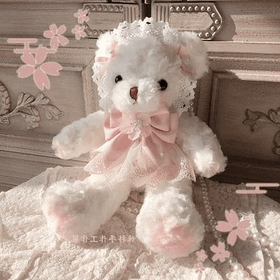 a white teddy bear wearing a pink dress and a lace hat is sitting on a bed .