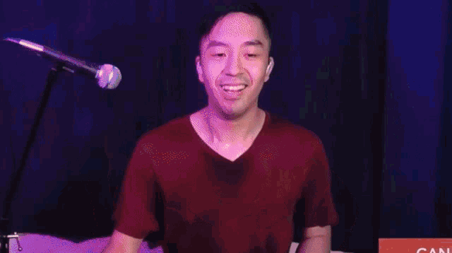 a man is playing drums in front of a microphone with the word can on the bottom