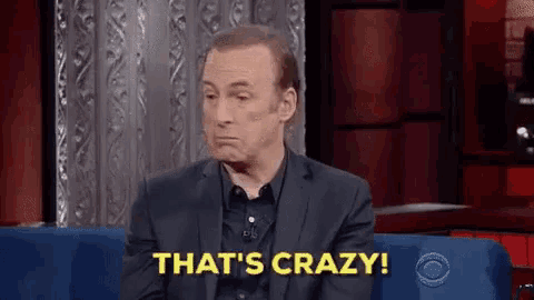 a man in a suit is sitting on a blue couch and saying `` that 's crazy ! ''