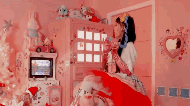 a girl in a red dress is sitting on a bed