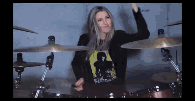 a woman wearing a shirt that says ' slipknot ' on it is playing drums