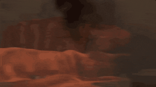 a blurry picture of a person laying on a bed with a blanket .