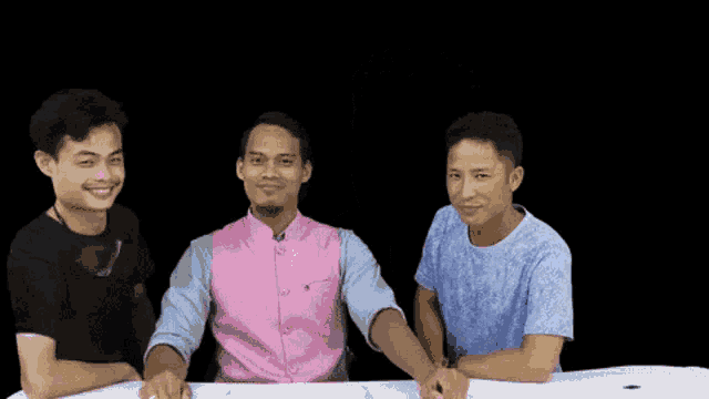 three men are sitting at a table with their arms crossed