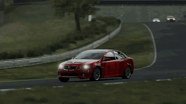 a red car is driving down a road with a few trees in the background