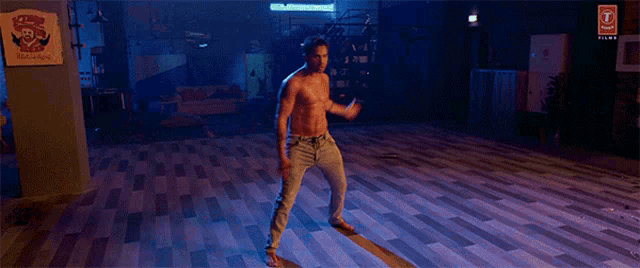 a man without a shirt is dancing in a dark room with a sign that says porsche on it