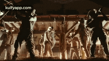 a group of cowboys are standing in a room holding guns and dancing .