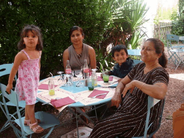 a little girl in a pink dress stands next to two women and a boy