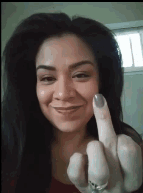 a woman with purple nails is smiling and giving the middle finger