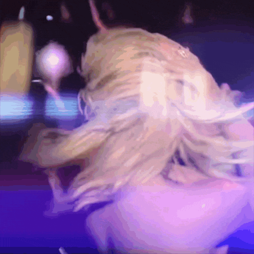 a woman with blonde hair is dancing in a purple room