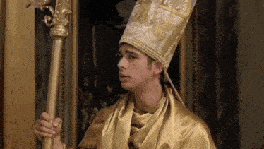 a man in a gold robe and hat is holding a gold pole