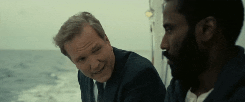 two men are sitting on a boat in the ocean and talking