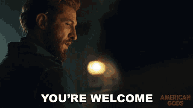 a man with a beard says " you 're welcome " in a dark room