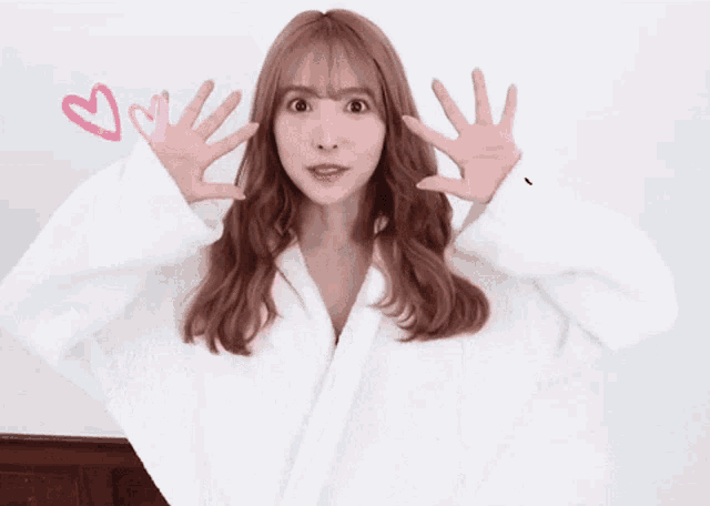a woman in a white robe is making a funny face with her hands outstretched .