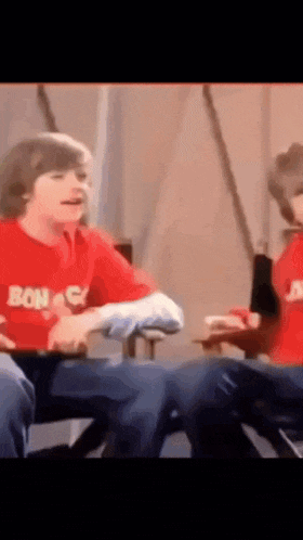 two boys wearing red shirts with the word bon on them are sitting next to each other