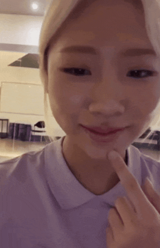 a woman in a purple shirt holds her finger to her mouth