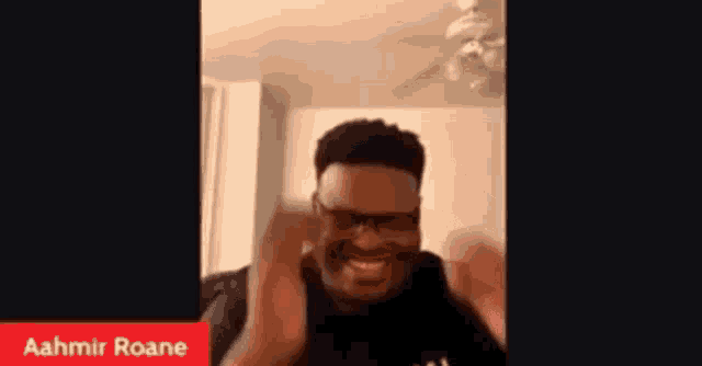 a man wearing glasses is making a funny face while sitting in a living room .