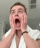 a young man with a towel around his neck is making a surprised face with his mouth open .