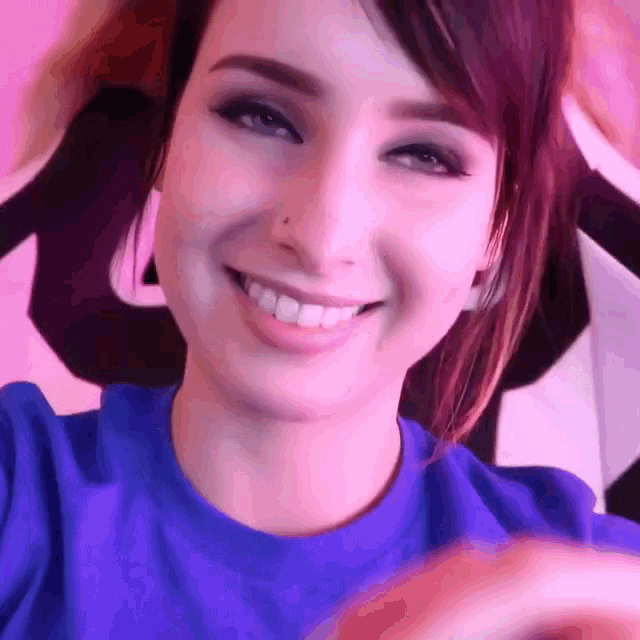 a close up of a woman 's face with a purple shirt on