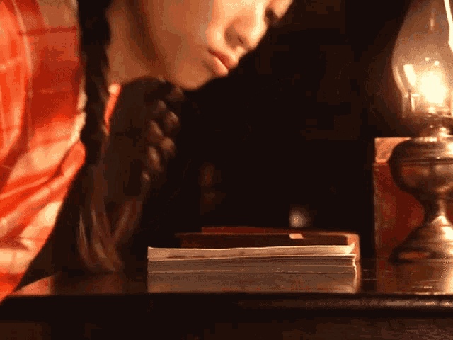 a woman sitting at a table with a lamp and a book