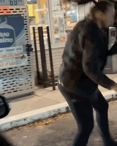 a woman stands in front of a blue rhino gas pump