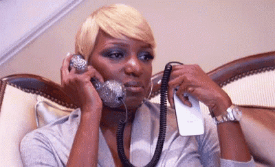 a woman is talking on a telephone while sitting on a bed .