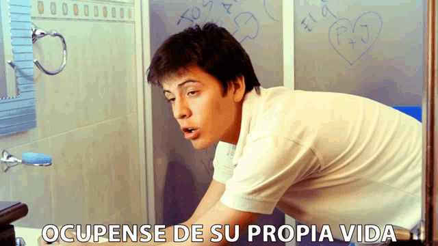 a man is washing his hands in a bathroom and the caption occupense de su propia vida is above him