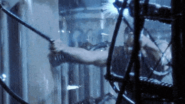 a man is holding a sword in a room with a lot of wires and tubes .