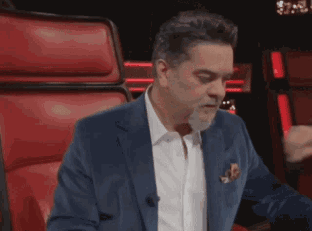 a man in a suit is sitting in a red chair