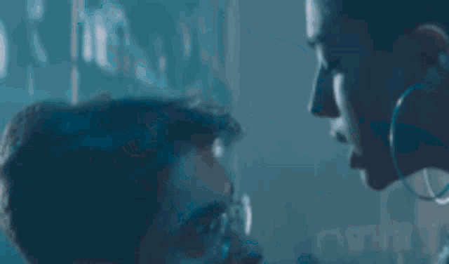a woman is kneeling on a man 's lap in a dark room .