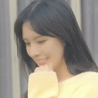 the woman is wearing a yellow sweater and smiling .