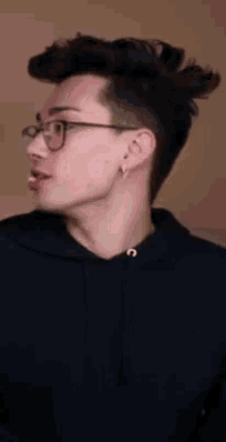 a young man wearing glasses and a black hoodie .