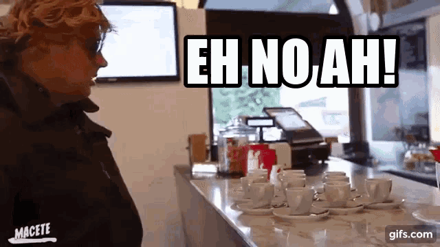a woman standing in front of a counter with a sign that says eh no ah on it
