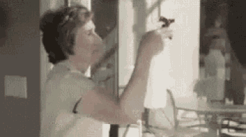 a woman is cleaning a window with a spray bottle in a room .