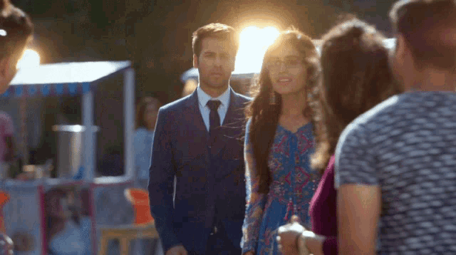 a man in a suit and tie stands next to a woman in a dress