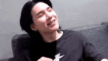 a close up of a person sitting on a couch with their eyes closed and smiling .